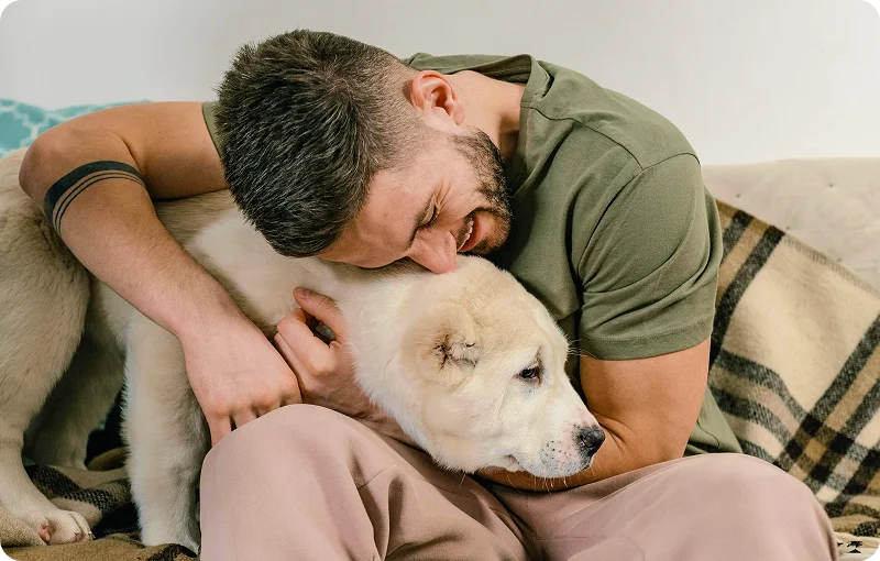 @lang('Homem abraça o seu cão num momento de afeto em casa, agora mais acolhedora após remodelações feitas com apoio do Poupança no Minuto.')